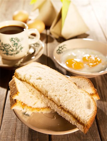 Traditional Chinese Malaysian style breakfast, kaya butter toast, nasi lemak and boiled eggs with coffee. Fractal on the cup is generic print. Soft focus setting with dramatic ambient light on dark wooden background. Foto de stock - Royalty-Free Super Valor e Assinatura, Número: 400-08223388