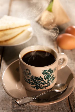 Traditional kopitiam style Malaysian coffee and breakfast with morning sunlight. Fractal on the cup is generic print. Soft focus setting with dramatic ambient light on dark wooden background. Foto de stock - Royalty-Free Super Valor e Assinatura, Número: 400-08223394