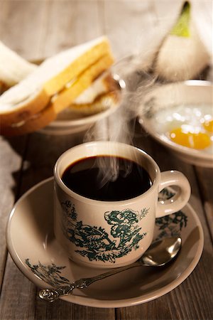 Traditional kopitiam style Malaysian coffee and breakfast with morning sunlight. Fractal on the cup is generic print. Soft focus dramatic ambient light over wood table. Photographie de stock - Aubaine LD & Abonnement, Code: 400-08223393