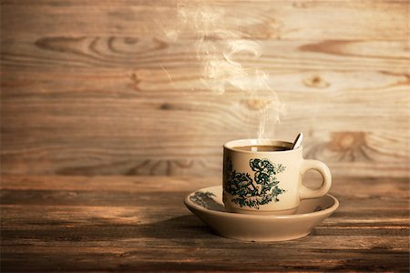 Steaming traditional oriental Chinese coffee in vintage cup and saucer.  Fractal on the cup is generic print. Soft focus setting with dramatic ambient light on dark wooden background. Foto de stock - Royalty-Free Super Valor e Assinatura, Número: 400-08223430