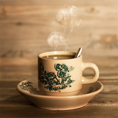 Close up steaming traditional oriental Chinese coffee in vintage mug and saucer.  Fractal on the cup is generic print. Soft focus setting with dramatic ambient light on dark wooden background. Photographie de stock - Aubaine LD & Abonnement, Code: 400-08223431