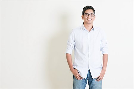 Portrait of handsome casual business Indian male smiling, hands in pocket, standing on plain background with shadow, copy space at side. Stock Photo - Budget Royalty-Free & Subscription, Code: 400-08223503
