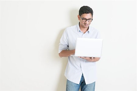 face man net - Portrait of handsome casual business Indian man using laptop computer, standing on plain background with shadow, copy space at side. Stock Photo - Budget Royalty-Free & Subscription, Code: 400-08223514