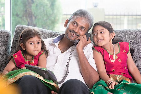 Husband making a phone call to wife while taking care of children at home. Asian Indian family at home. Stock Photo - Budget Royalty-Free & Subscription, Code: 400-08223588