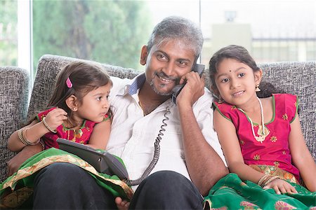 Daddy  making a phone call to mommy while taking care of children at home. Asian Indian family at home. Stock Photo - Budget Royalty-Free & Subscription, Code: 400-08223589