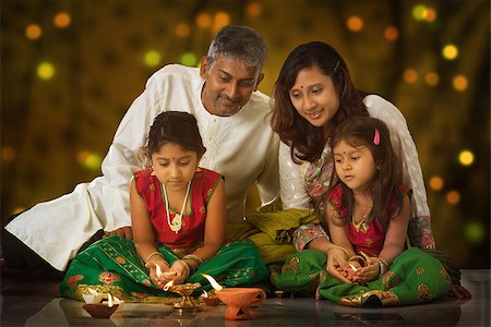 simsearch:400-08223620,k - Indian family in traditional sari lighting oil lamp and celebrating Diwali, fesitval of lights inside a temple. Little girl hands holding oil lamp indoors. Stock Photo - Budget Royalty-Free & Subscription, Code: 400-08223605