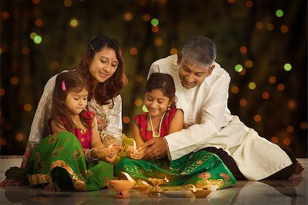 simsearch:400-08223620,k - Indian family in traditional sari lighting oil lamp and celebrating Diwali or deepavali, fesitval of lights at home. Little girl hands holding oil lamp indoors. Stock Photo - Budget Royalty-Free & Subscription, Code: 400-08223606