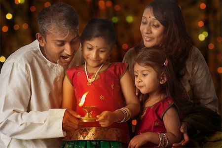 simsearch:400-08223620,k - Indian family in traditional sari lighting oil lamp and celebrating Diwali, fesitval of lights inside a temple. Little girl hands holding oil lamp with beautiful bokeh background. Stock Photo - Budget Royalty-Free & Subscription, Code: 400-08223603