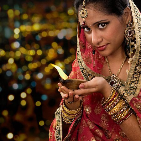 people praying on diwali images - Indian girl in traditional sari lighting oil lamp and celebrating Diwali or deepavali, fesitval of lights at temple. Woman hands holding oil lamp, beautiful lights bokeh background. Stock Photo - Budget Royalty-Free & Subscription, Code: 400-08223700