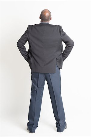 Rear view full body mature Indian business man hands on waist and looking up , standing on plain background. Stock Photo - Budget Royalty-Free & Subscription, Code: 400-08223790