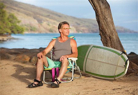 Handsome male surfer sitting on beach near his surfboard Stock Photo - Budget Royalty-Free & Subscription, Code: 400-08254689