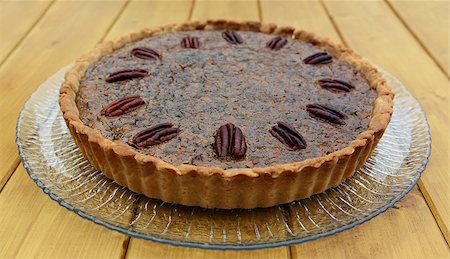 pecan pie - Whole freshly baked pecan pie on a glass plate, on a wooden table Stock Photo - Budget Royalty-Free & Subscription, Code: 400-08257259