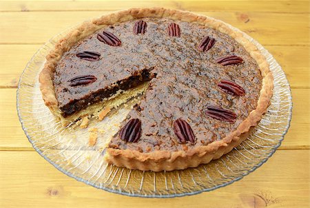 pecan pie - Traditional pecan pie on a glass plate with one slice taken Stock Photo - Budget Royalty-Free & Subscription, Code: 400-08257261