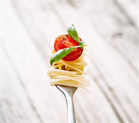 delicious pasta - Italian cuisine. Pasta on fork. Pasta with olive oil, garlic, basil and tomatoes. Spaghetti with tomatoes Stock Photo - Budget Royalty-Free & Subscription, Code: 400-08250279