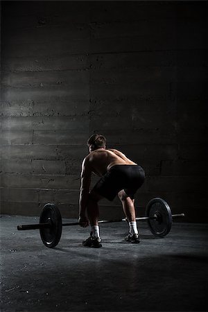 Portrait of a handsome athlete from behind. Athlete leaned over to the bar and took her hands behind the neck. Studio shots in the dark tone. Stock Photo - Budget Royalty-Free & Subscription, Code: 400-08250441