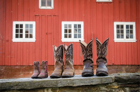 A variety of sizes of cowboy boots in front of a red barn. Stock Photo - Budget Royalty-Free & Subscription, Code: 400-08250623