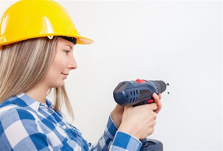 simsearch:400-05704663,k - Young woman drilling a hole in the wall and wearing a protective helmet Stock Photo - Budget Royalty-Free & Subscription, Code: 400-08251822