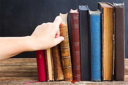 Hand taking book from wooden bookshelf  with row of antique books Stock Photo - Budget Royalty-Free & Subscription, Code: 400-08252481