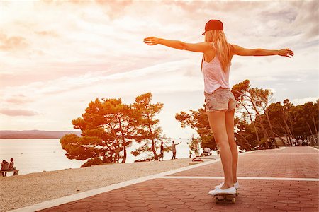 Young carefree woman riding a skateboard along the coast at sunset Stock Photo - Budget Royalty-Free & Subscription, Code: 400-08253093