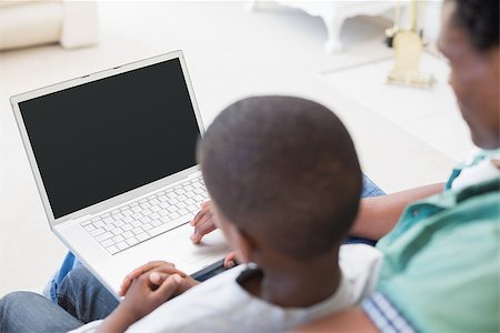 Father and son using laptop on the couch at home in the living room Stock Photo - Budget Royalty-Free & Subscription, Code: 400-08265496