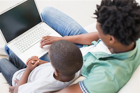 Father and son using laptop on the couch at home in the living room Stock Photo - Budget Royalty-Free & Subscription, Code: 400-08265497