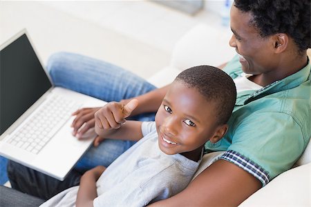 Father and son using laptop on the couch at home in the living room Stock Photo - Budget Royalty-Free & Subscription, Code: 400-08265498