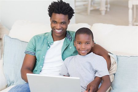 Father and son using laptop on the couch at home in the living room Stock Photo - Budget Royalty-Free & Subscription, Code: 400-08265500