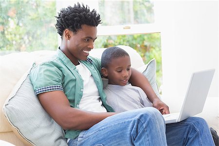 Father and son using laptop on the couch at home in the living room Stock Photo - Budget Royalty-Free & Subscription, Code: 400-08265501