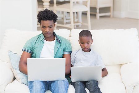 Father and son using laptops on the couch at home in the living room Stock Photo - Budget Royalty-Free & Subscription, Code: 400-08265525