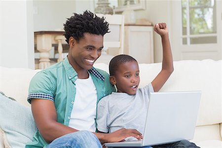 Father and son using laptop on the couch at home in the living room Stock Photo - Budget Royalty-Free & Subscription, Code: 400-08265522