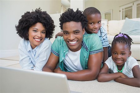 Happy family lying on the floor using laptop at home in the living room Stock Photo - Budget Royalty-Free & Subscription, Code: 400-08265538