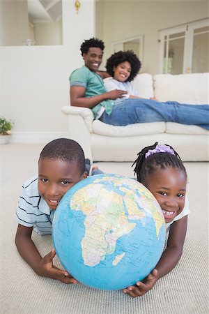 Happy siblings lying on the floor holding globe at home in the living room Stock Photo - Budget Royalty-Free & Subscription, Code: 400-08265551