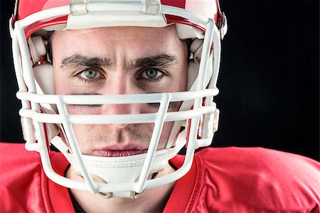 simsearch:6109-08389992,k - Portrait of a serious american football player taking his helmet looking at camera with black background Stock Photo - Budget Royalty-Free & Subscription, Code: 400-08265655