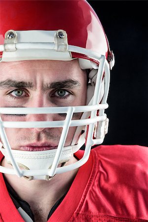 simsearch:625-02931241,k - Portrait of a serious american football player taking his helmet looking at camera with black background Fotografie stock - Microstock e Abbonamento, Codice: 400-08265656