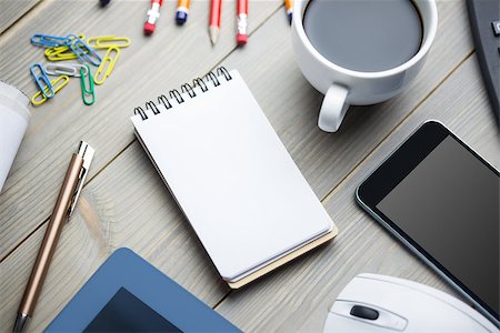 Notepad next to the cup of the coffe smartphone mouse and tablet at the office Stock Photo - Budget Royalty-Free & Subscription, Code: 400-08265680