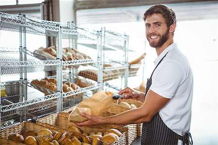 simsearch:400-08265905,k - Cheerful worker standing and presenting a bread at the bakery Foto de stock - Super Valor sin royalties y Suscripción, Código: 400-08265890