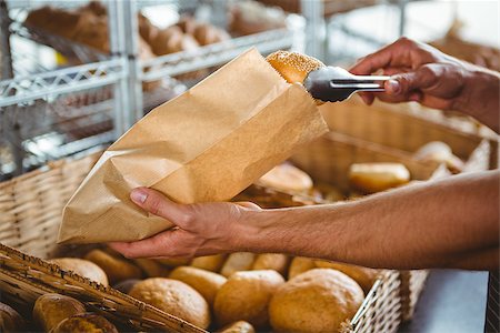 simsearch:400-08265905,k - Smiling waiter taking bread with tongs at the bakery Foto de stock - Super Valor sin royalties y Suscripción, Código: 400-08265891