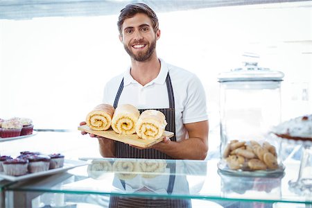 simsearch:400-08265905,k - Smiling worker holding pastry behind the counter at bakery Foto de stock - Super Valor sin royalties y Suscripción, Código: 400-08265926