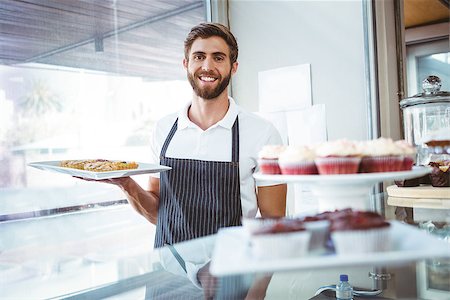 simsearch:400-08265905,k - Smiling worker holding pastry behind the counter at bakery Foto de stock - Super Valor sin royalties y Suscripción, Código: 400-08265930