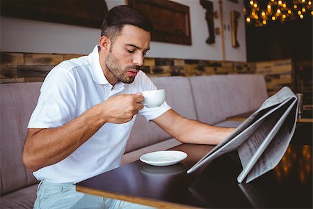 Young man drinking cup of coffee reading newspaper at the cafe Stock Photo - Budget Royalty-Free & Subscription, Code: 400-08265960