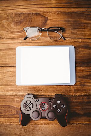 Tablet next to joystick and glasses on wooden table Stock Photo - Budget Royalty-Free & Subscription, Code: 400-08266037