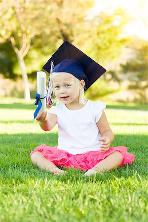 Cute Little Girl In Grass Wearing Graduation Cap Holding Diploma With Ribbon. Stock Photo - Budget Royalty-Free & Subscription, Code: 400-08260014