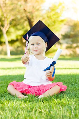 Cute Little Girl In Grass Wearing Graduation Cap Holding Diploma With Ribbon. Stock Photo - Budget Royalty-Free & Subscription, Code: 400-08260015