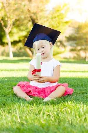 Cute Little Girl In Grass Wearing Graduation Cap Holding Diploma With Ribbon. Stock Photo - Budget Royalty-Free & Subscription, Code: 400-08260013