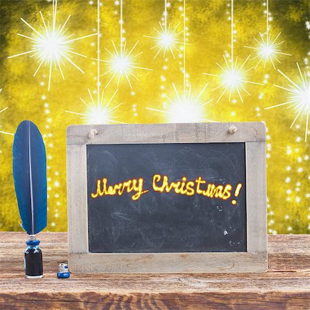 simsearch:400-06853377,k - Blue  feather pen in inkwell on  aged wooden table with merry christmas on blackboard,  glowing christmas background Stock Photo - Budget Royalty-Free & Subscription, Code: 400-08261756