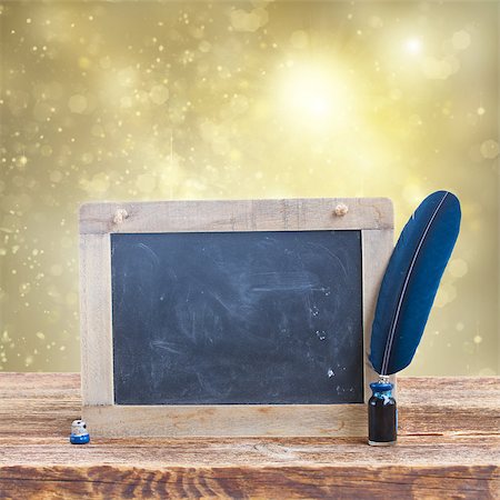 simsearch:400-06853377,k - Blue  feather pen in inkwell on  aged wooden table with empty blackboard on glowing christmas background Stock Photo - Budget Royalty-Free & Subscription, Code: 400-08261757