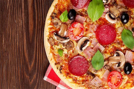 simsearch:400-08291219,k - Italian pizza with pepperoni, tomatoes, olives and basil on wooden table. Top view with copy space Stock Photo - Budget Royalty-Free & Subscription, Code: 400-08284688