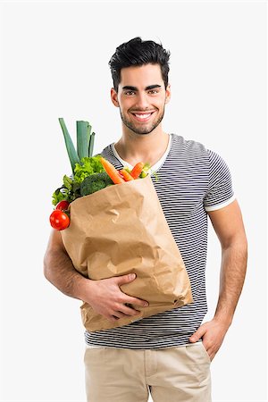 Handsome young man carrying a bag full of vegetables, isolated over gray background Stock Photo - Budget Royalty-Free & Subscription, Code: 400-08286092