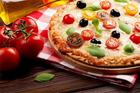 simsearch:400-08960199,k - Italian pizza with cheese, tomatoes, olives and basil on wooden table Stock Photo - Budget Royalty-Free & Subscription, Code: 400-08286452