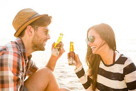 sunset hang out - Young couple at the beach having fun, laughing and drinking beer Foto de stock - Super Valor sin royalties y Suscripción, Código: 400-08287044